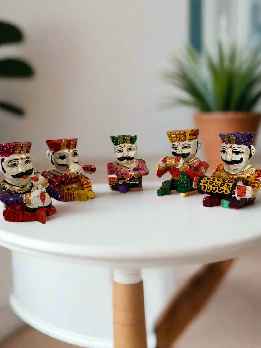 Five colorful figurines of characters with different attires on a white surface.